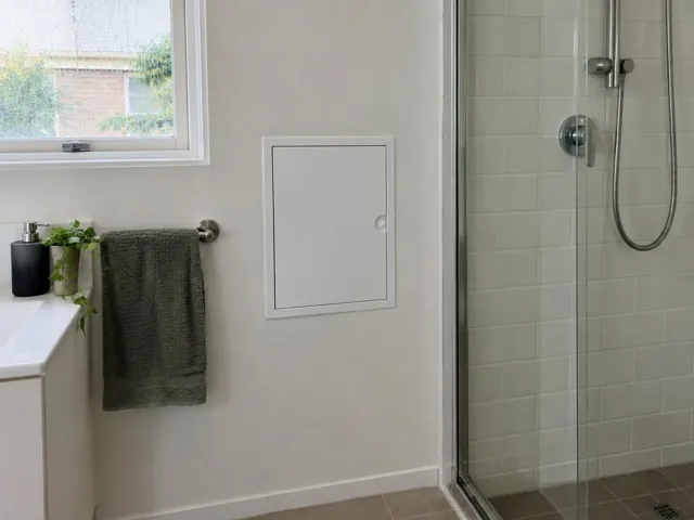Neat access panel on a bathroom wall beside a shower and towel rail in Rydalmere